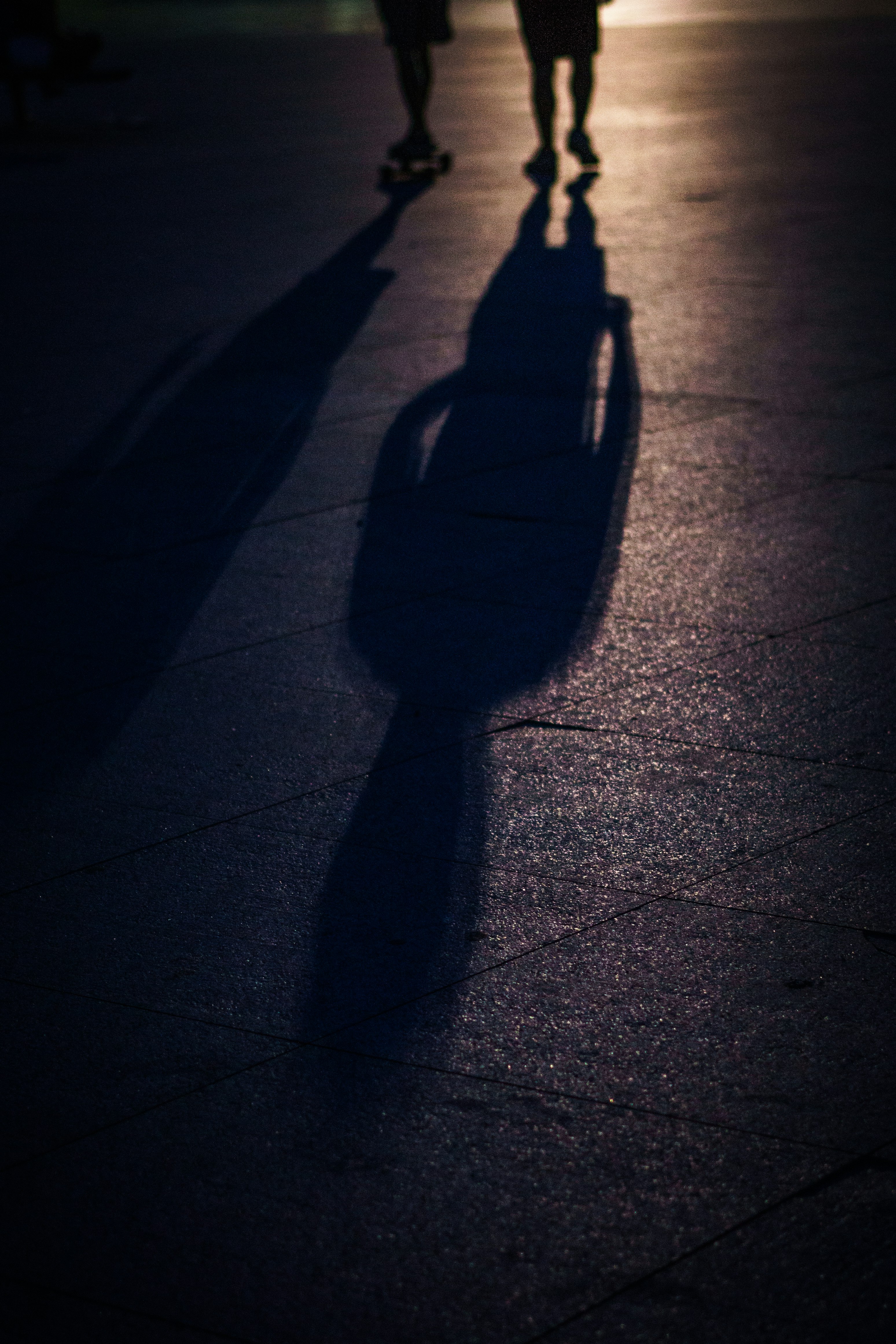 two people walking with shadows on road